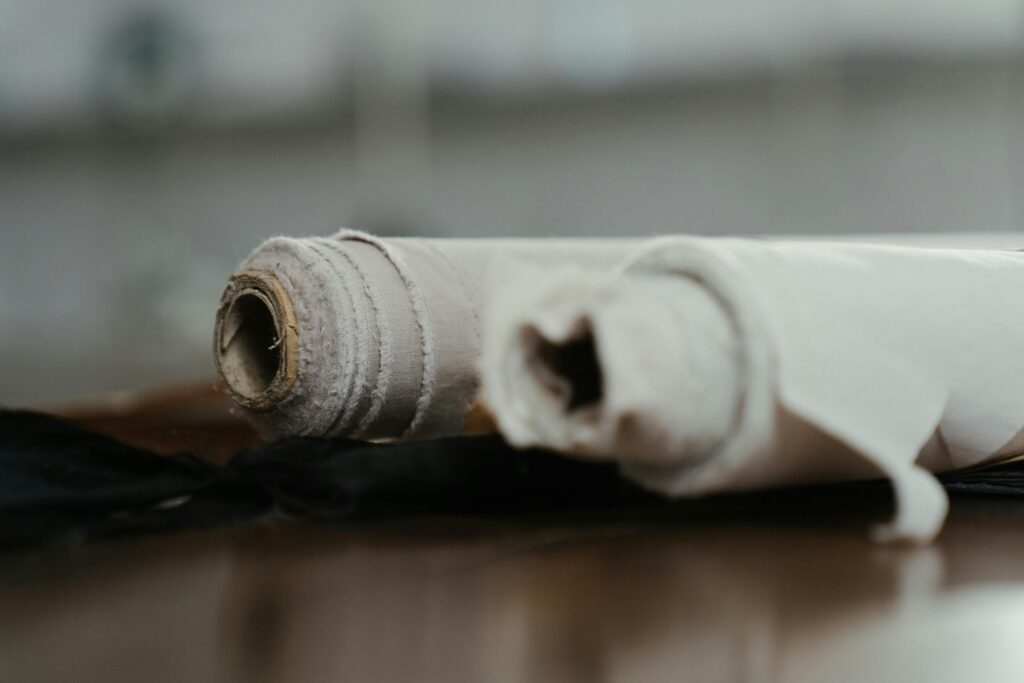 Rolled fabrics on a workshop table, highlighting textures and materials in a sewing environment.